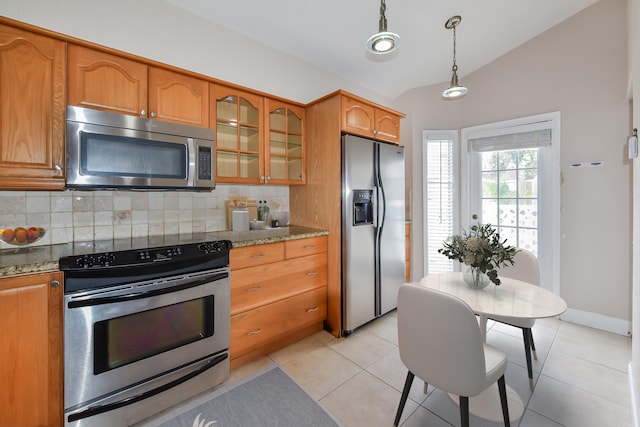 kitchen with stainless steel appliances, vaulted ceiling, light stone counters, light tile patterned floors, and decorative backsplash