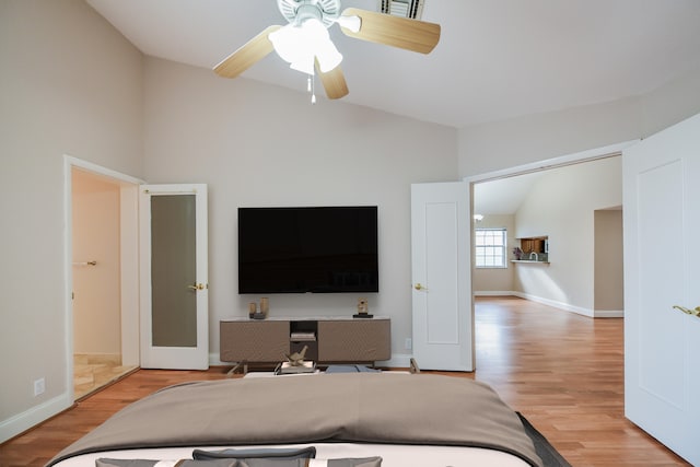 bedroom with ceiling fan, light hardwood / wood-style flooring, and lofted ceiling