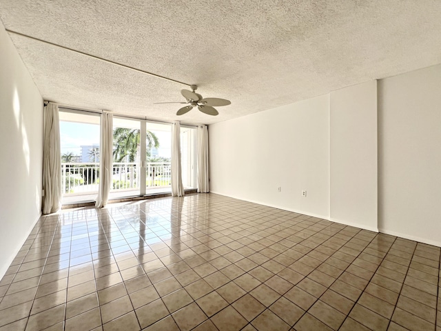 spare room featuring a textured ceiling, a wall of windows, tile patterned floors, and ceiling fan