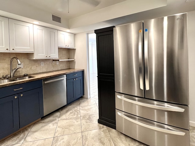 kitchen featuring white cabinets, blue cabinets, backsplash, and stainless steel appliances