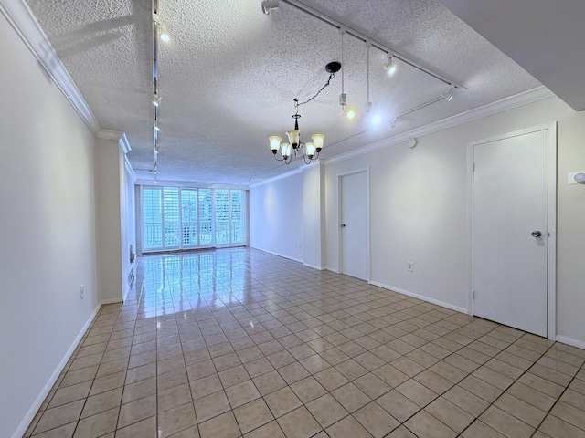 spare room with crown molding, a notable chandelier, track lighting, a textured ceiling, and light tile patterned flooring