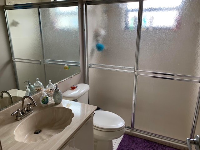 bathroom featuring vanity, a shower with shower door, toilet, and tile patterned floors