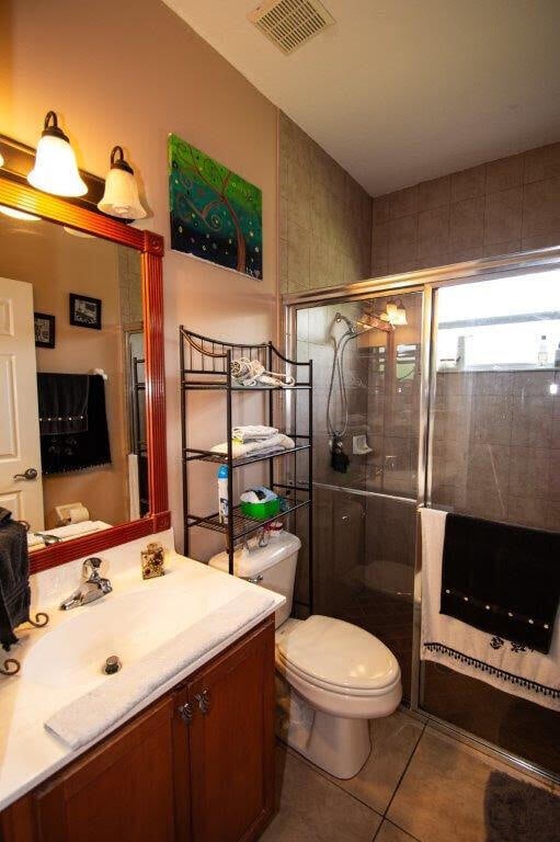 bathroom featuring vanity, toilet, a shower with shower door, and tile patterned flooring