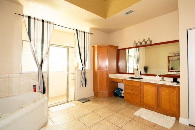 bathroom with tile patterned floors, independent shower and bath, a textured ceiling, and vanity