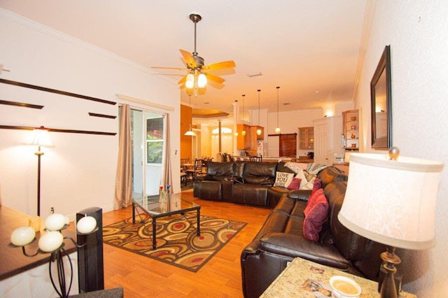 living room with light wood-type flooring, ceiling fan, and crown molding