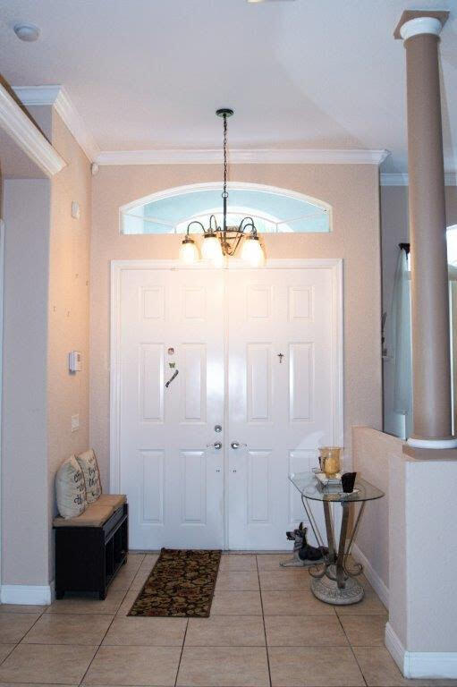 entryway with ornamental molding, decorative columns, and tile patterned floors