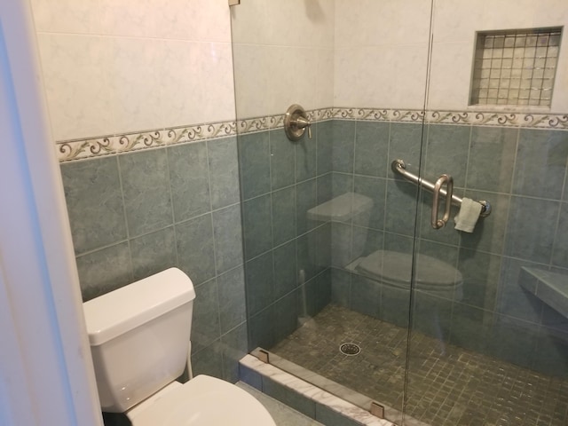 bathroom featuring tile walls, an enclosed shower, and toilet