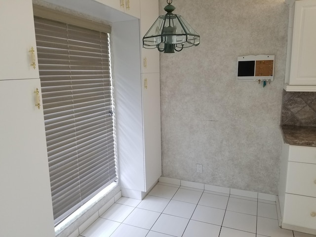 unfurnished dining area featuring a notable chandelier and light tile patterned flooring