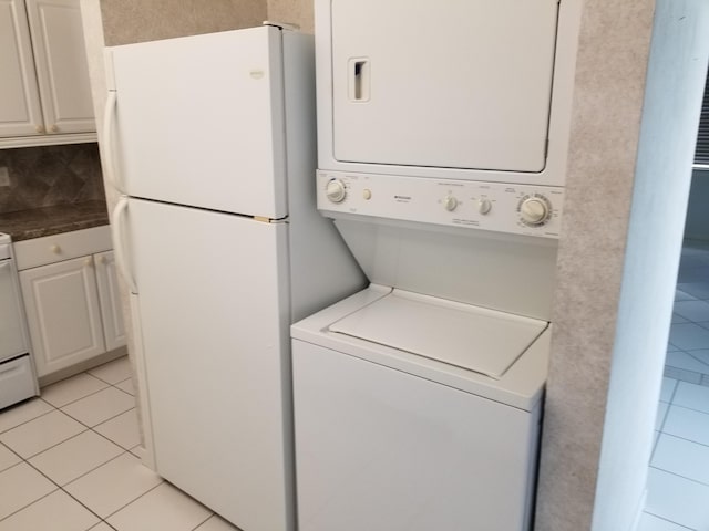 clothes washing area with light tile patterned floors and stacked washer and clothes dryer