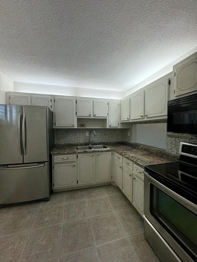 kitchen with tasteful backsplash, appliances with stainless steel finishes, sink, and a textured ceiling