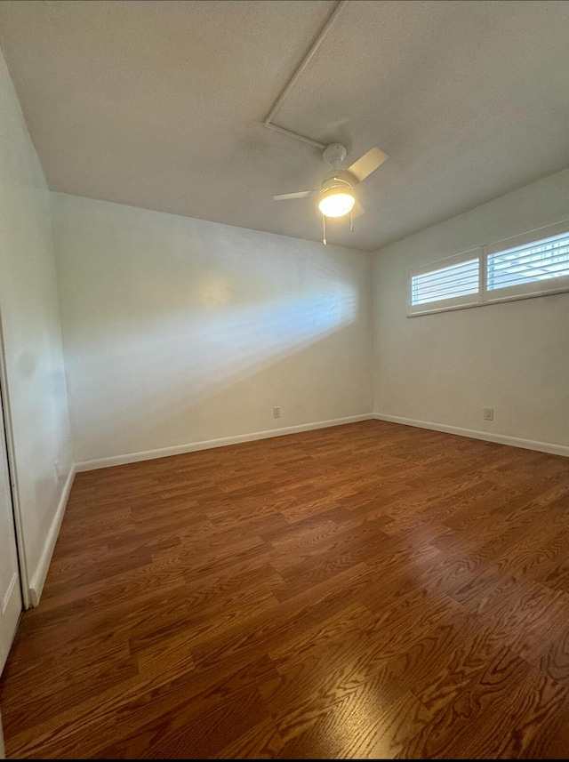 empty room featuring dark wood-type flooring and ceiling fan