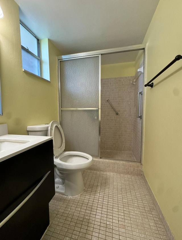 bathroom featuring tile patterned flooring, vanity, toilet, and a shower with shower door