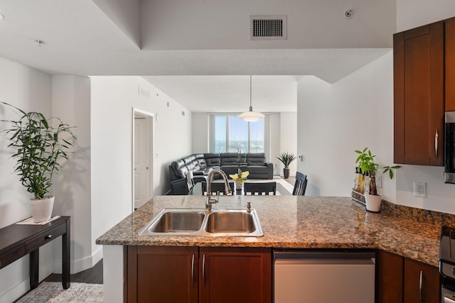 kitchen featuring dark stone counters, stainless steel appliances, light hardwood / wood-style flooring, sink, and hanging light fixtures