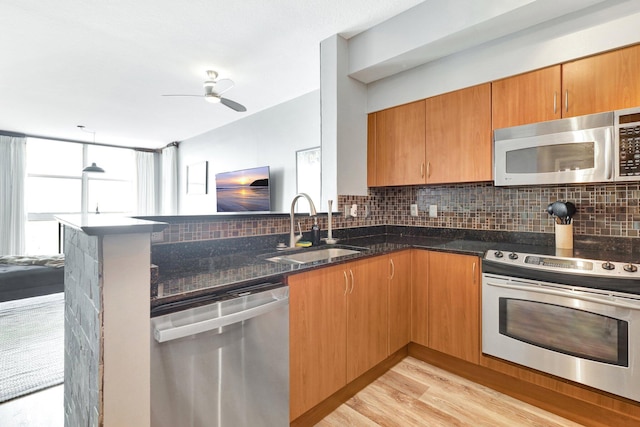 kitchen featuring stainless steel appliances, dark stone countertops, light hardwood / wood-style floors, sink, and ceiling fan