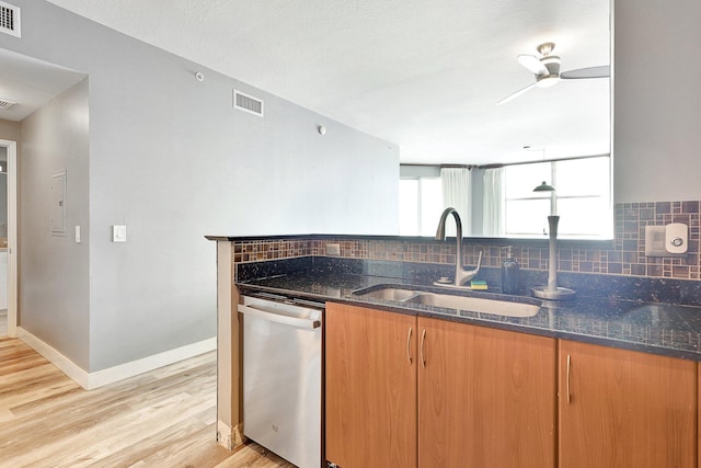 kitchen with light hardwood / wood-style floors, ceiling fan, dark stone counters, stainless steel dishwasher, and sink