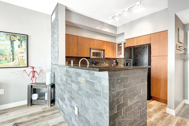 kitchen featuring backsplash, light hardwood / wood-style floors, kitchen peninsula, sink, and black fridge with ice dispenser