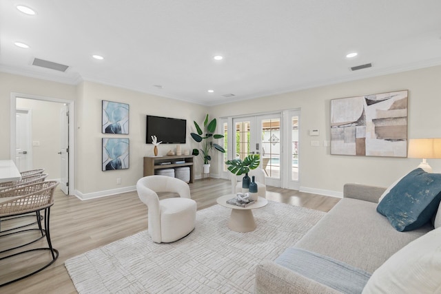 living room featuring light wood-type flooring, ornamental molding, and french doors