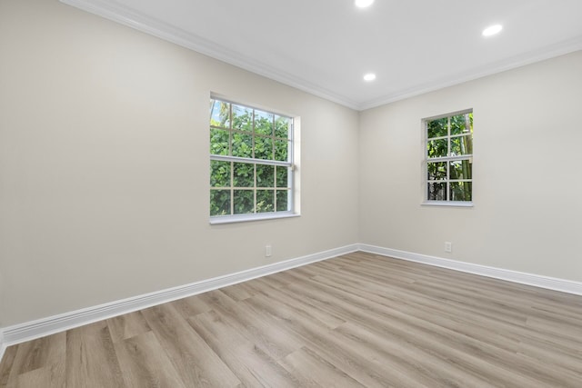 spare room featuring a wealth of natural light, ornamental molding, and light hardwood / wood-style flooring