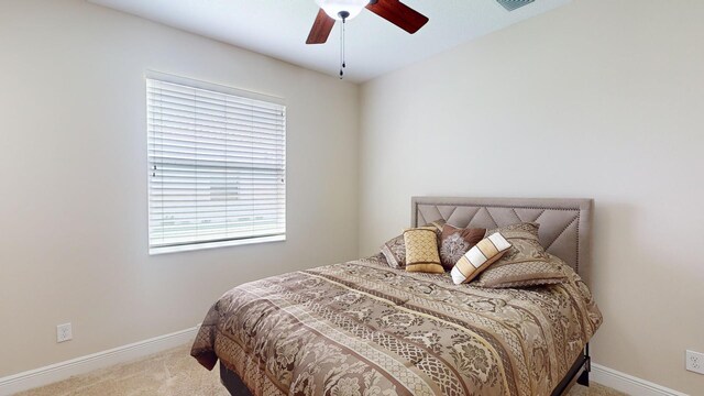 bedroom with ceiling fan, multiple windows, and light carpet