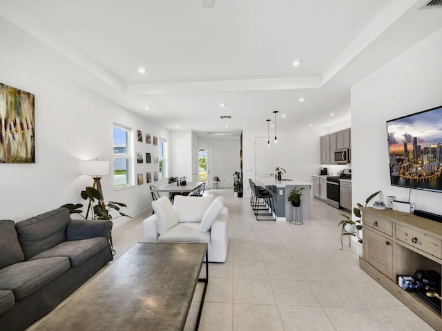 living room with light tile patterned flooring and a tray ceiling