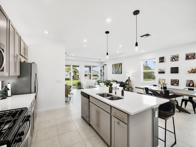 kitchen featuring a center island with sink, stainless steel appliances, decorative light fixtures, and a wealth of natural light