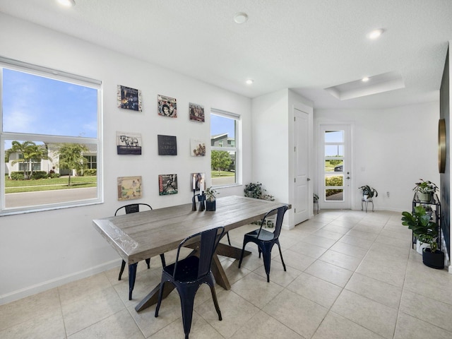 dining room with a textured ceiling, a healthy amount of sunlight, and light tile patterned floors