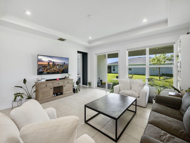 living room featuring a raised ceiling and light tile patterned floors