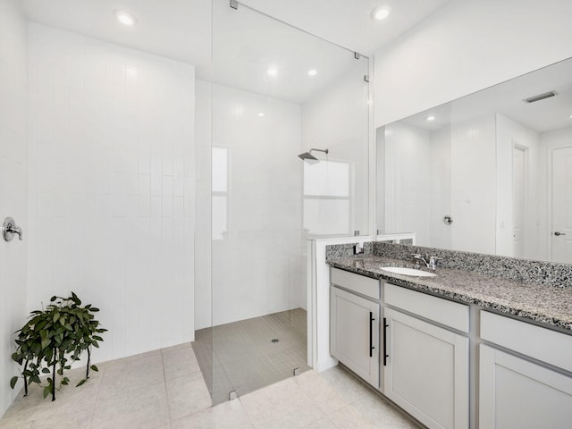 bathroom featuring vanity, tile patterned floors, and a tile shower