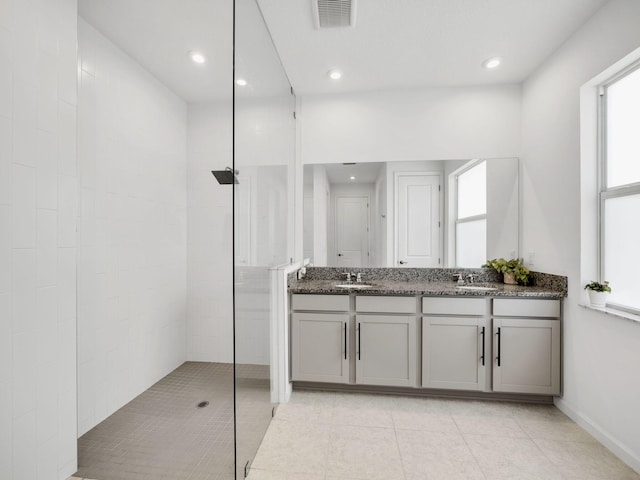 bathroom with tile patterned flooring, a tile shower, and dual bowl vanity