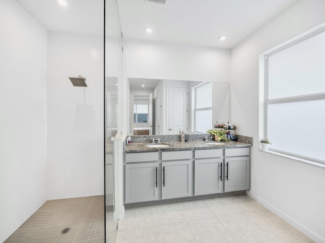 bathroom with tiled shower, vanity, and tile patterned floors