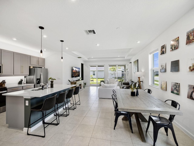 dining space featuring a raised ceiling, sink, and light tile patterned floors