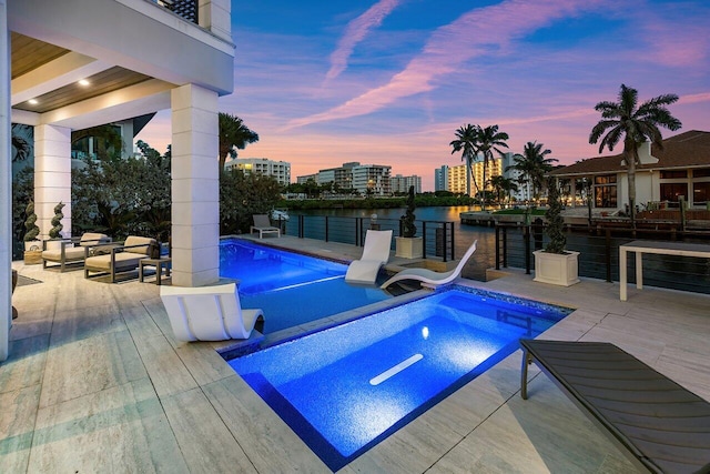 pool at dusk with a patio and a water view