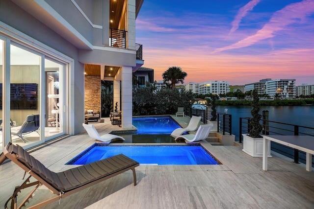 pool at dusk with a patio and a water view