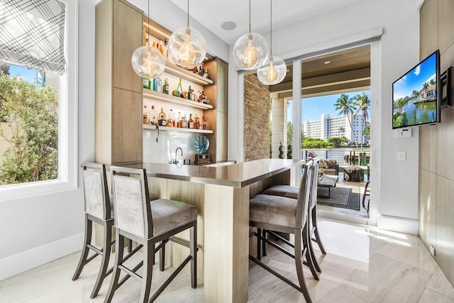 bar with pendant lighting, light brown cabinets, and light tile patterned flooring