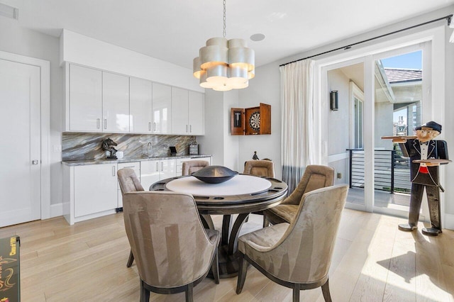 dining space with a chandelier, sink, and light hardwood / wood-style floors