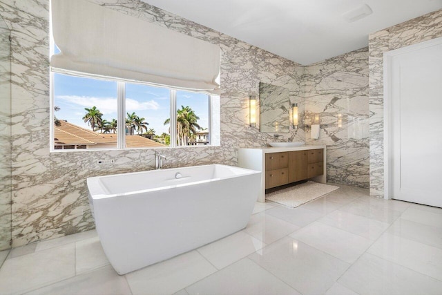 bathroom with tile walls, a washtub, vanity, and tile patterned floors