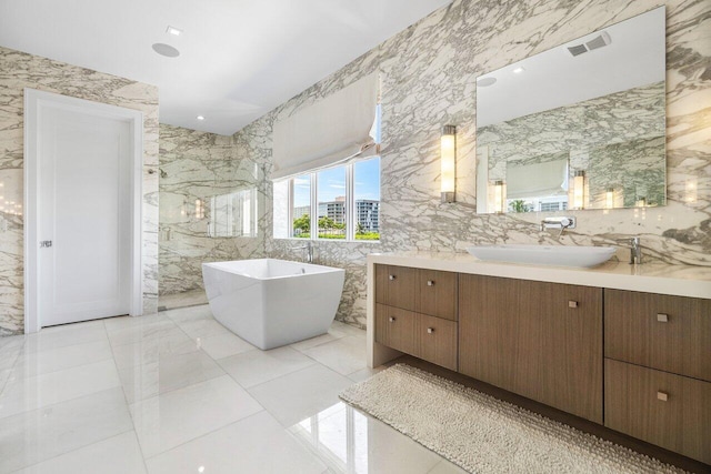 bathroom featuring tile walls, vanity, a tub to relax in, and tile patterned floors