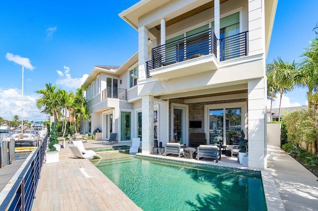 rear view of property with outdoor lounge area, a balcony, a fenced in pool, and a patio