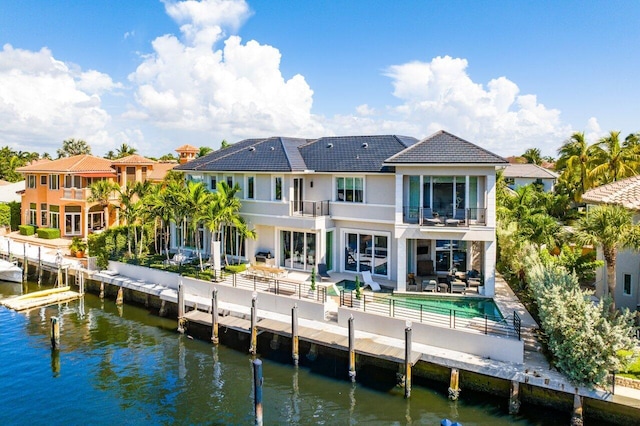 rear view of house featuring a water view, a patio, and a balcony