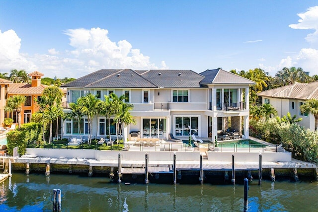 rear view of house featuring a water view, a patio, and a balcony