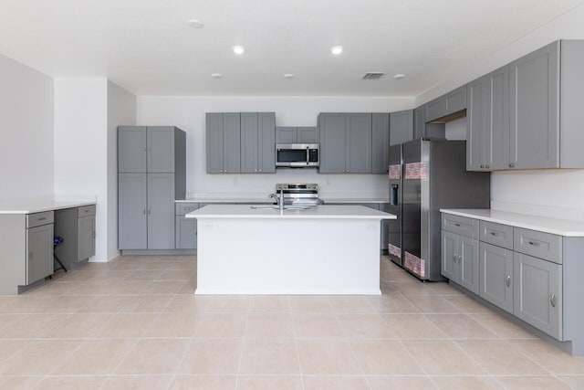 kitchen with gray cabinetry, a center island with sink, and appliances with stainless steel finishes