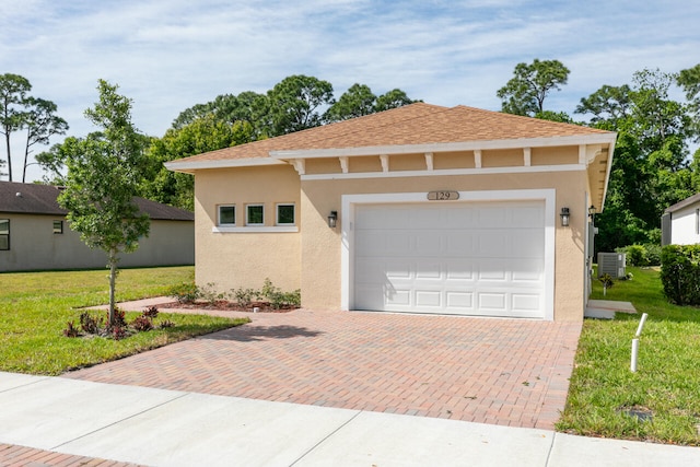 view of front of property featuring a garage, central air condition unit, and a front yard