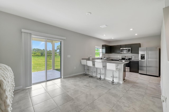 kitchen with baseboards, a peninsula, a breakfast bar, stainless steel appliances, and light countertops