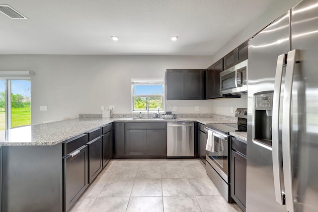 kitchen featuring visible vents, light tile patterned floors, stainless steel appliances, a peninsula, and a sink