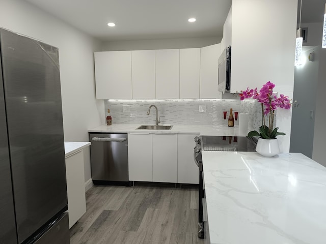 193 Burgundy E, Delray Beach, FL 33484 - kitchen featuring decorative backsplash, a sink, light wood-style floors, white cabinets, and appliances with stainless steel finishes