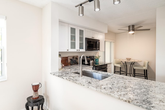 kitchen featuring white cabinetry, sink, light stone counters, and a textured ceiling