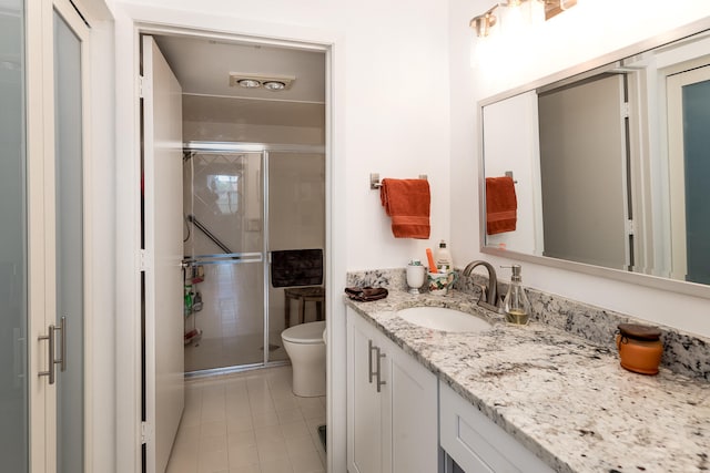 bathroom featuring tile patterned flooring, vanity, toilet, and walk in shower