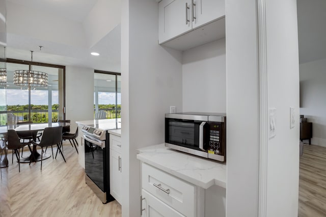 5279 Fountains Dr S Unit 602, Lake Worth, FL 33467 - kitchen featuring white cabinets, light wood-style flooring, light stone countertops, and stainless steel appliances