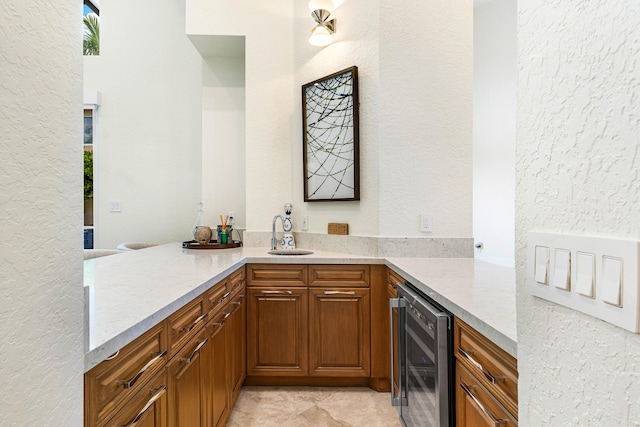 kitchen with kitchen peninsula, wine cooler, light stone countertops, and sink