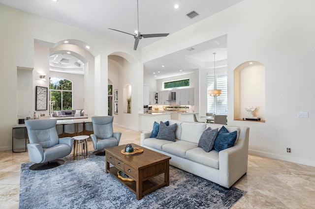 living room with a towering ceiling and ceiling fan